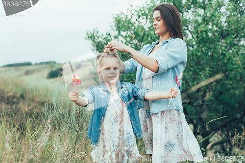 Image of The young mother and daughter on green grass background 