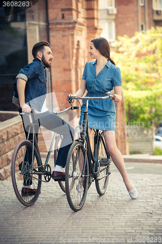 Image of Young couple sitting on a bicycle opposite the city 