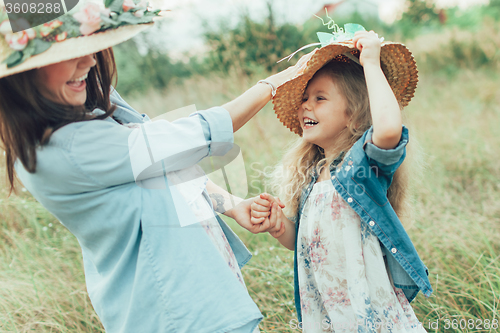 Image of The young mother and daughter on green grass background 