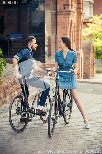 Image of Young couple sitting on a bicycle opposite city 