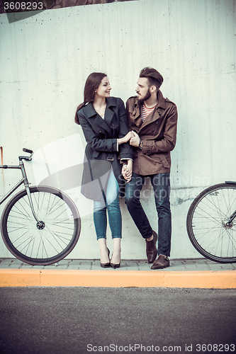 Image of Young couple with a bicycle opposite city 