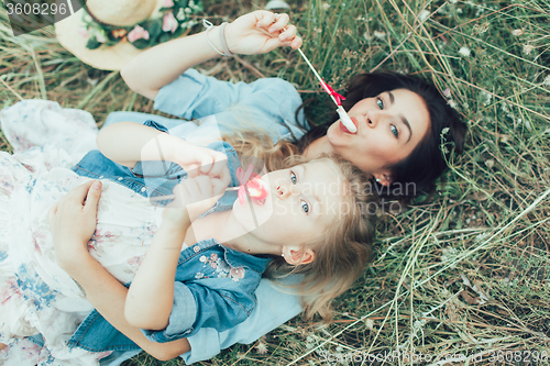 Image of The young mother and daughter on green grass background 