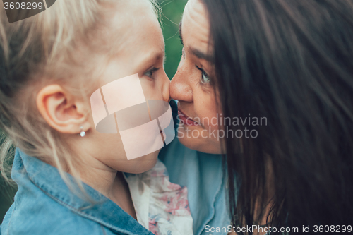 Image of The young mother and daughter on green grass background 