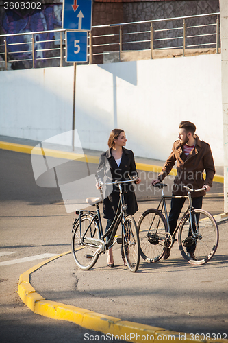 Image of Young couple with on a bicycle opposite city 