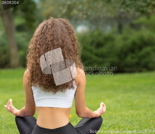 Image of Pretty woman sitting back doing yoga meditation