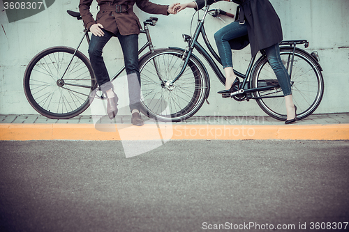 Image of Young couple with a bicycle opposite city 