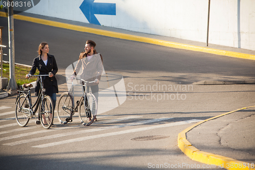 Image of Young couple with a bicycle opposite city 