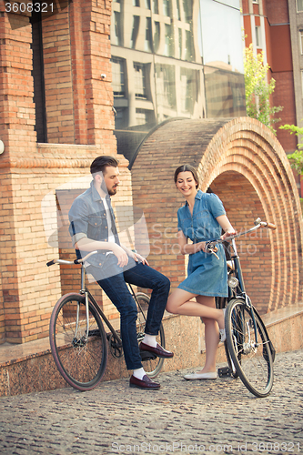 Image of Young couple sitting on a bicycle opposite city 