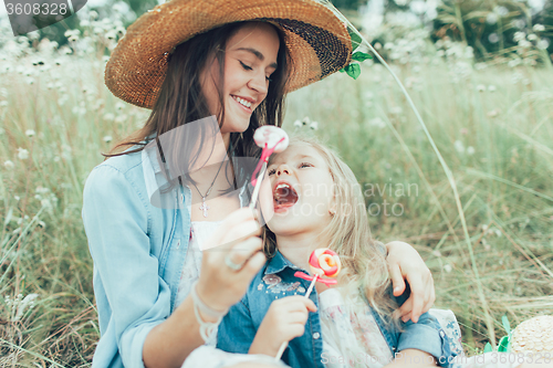 Image of The young mother and daughter on green grass background 