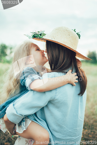 Image of The young mother and daughter on green grass background 