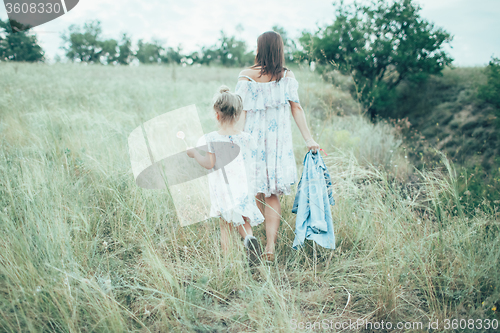Image of The young mother and daughter on green grass background 