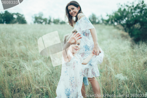 Image of The young mother and daughter on green grass background 