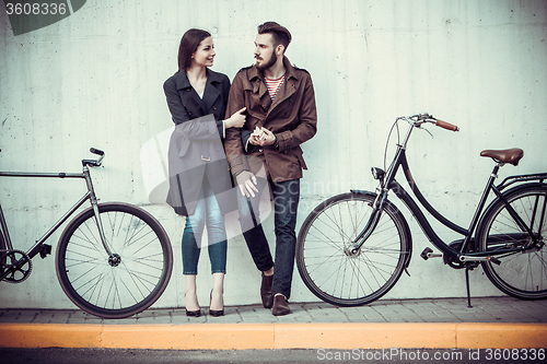 Image of Young couple with a bicycle opposite city 