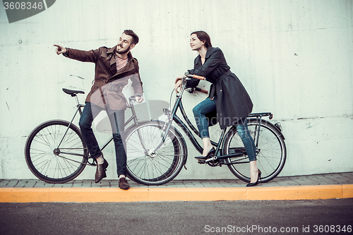 Image of Young couple with a bicycle opposite city 