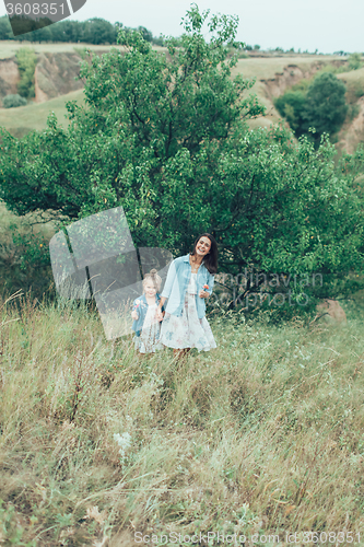 Image of The young mother and daughter on green grass background 