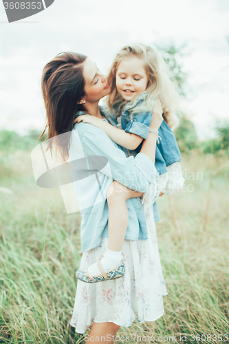 Image of The young mother and daughter on green grass background 