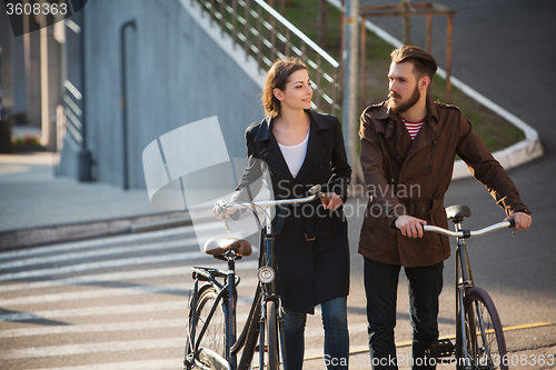 Image of Young couple with on a bicycle opposite city 