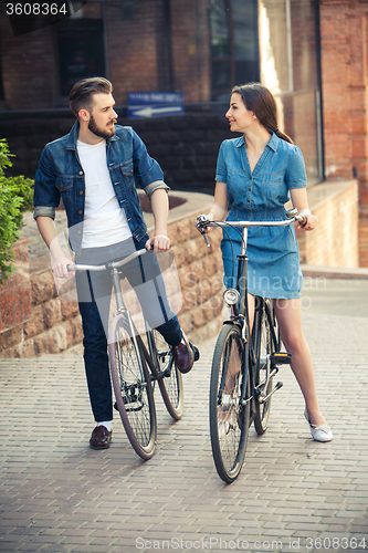 Image of Young couple sitting on a bicycle opposite city 