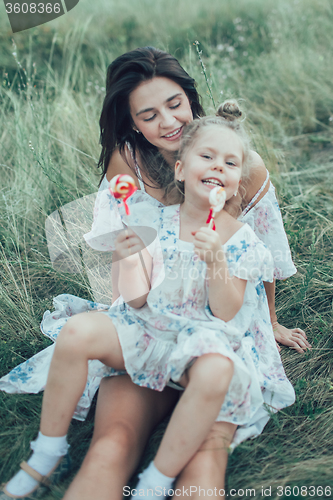 Image of The young mother and daughter on green grass background 