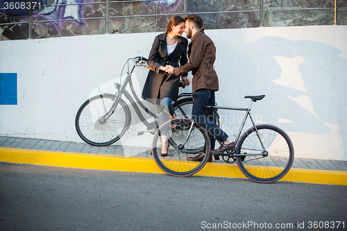 Image of Young couple with a bicycle opposite city 