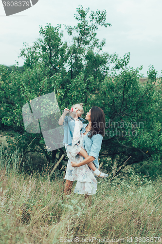 Image of The young mother and daughter on green grass background 