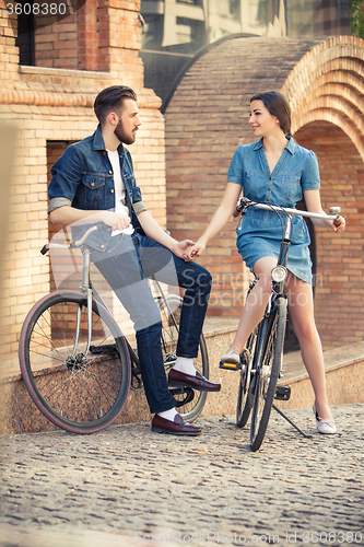 Image of Young couple sitting on a bicycle opposite city 