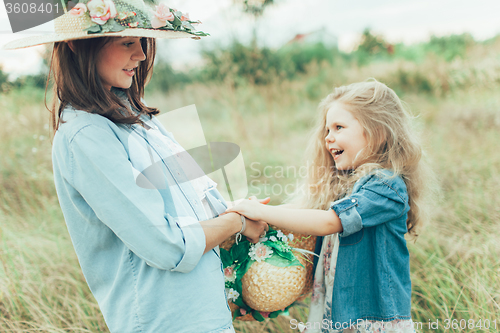 Image of The young mother and daughter on green grass background 