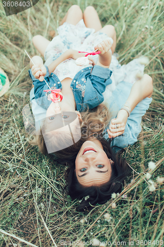 Image of The young mother and daughter on green grass background 