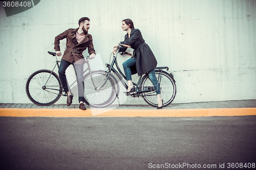 Image of Young couple with a bicycle opposite city 