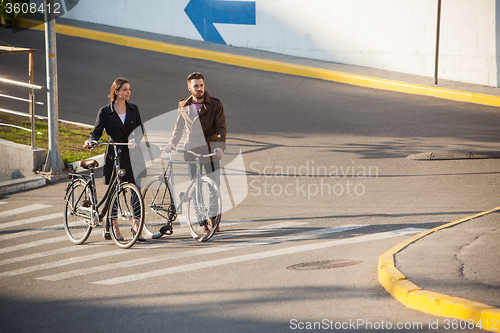 Image of Young couple with a bicycle opposite city 