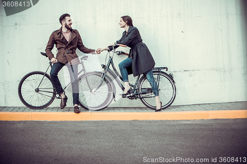 Image of Young couple with a bicycle opposite city 