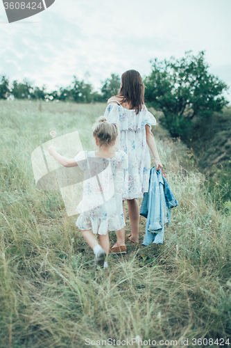 Image of The young mother and daughter on green grass background 