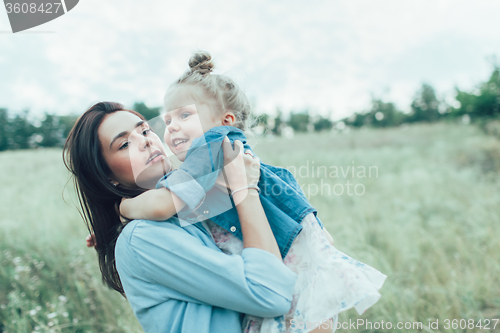 Image of The young mother and daughter on green grass background 