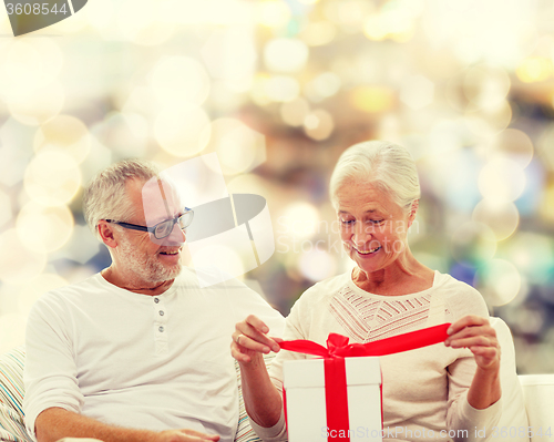 Image of happy senior couple with gift box at home