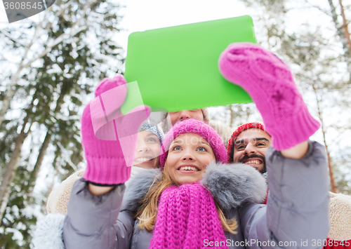 Image of smiling friends with tablet pc in winter forest