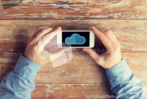 Image of close up of male hands with cloud on smartphone