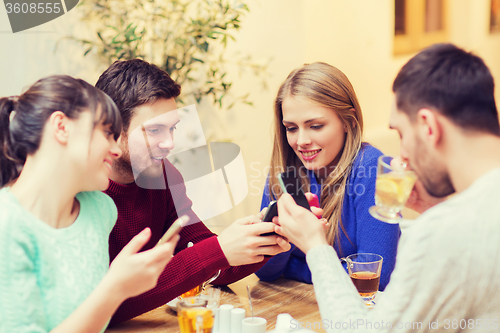 Image of group of friends with smartphones meeting at cafe