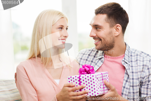 Image of happy man giving woman gift box at home