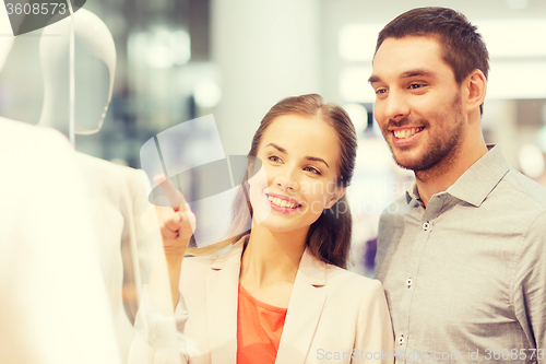 Image of happy couple pointing finger to shop window