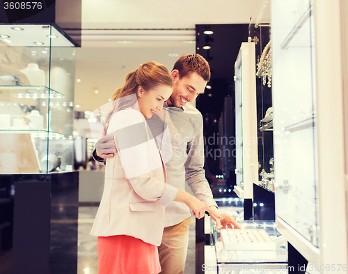 Image of happy couple choosing engagement ring in mall