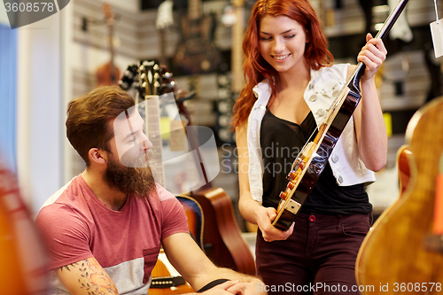 Image of couple of musicians with guitar at music store