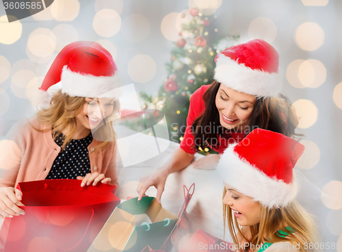 Image of happy women in santa hats with christmas gifts
