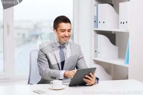 Image of smiling businessman with tablet pc and coffee cup