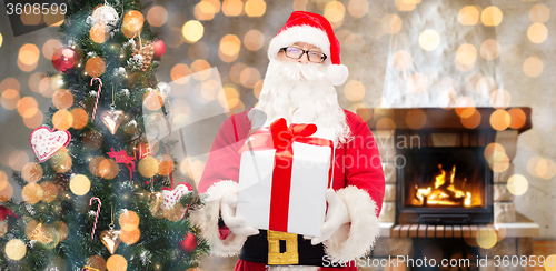 Image of santa claus with gift and christmas tree at home