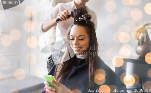 Image of happy woman with stylist making hairdo at salon