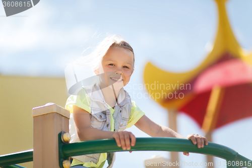 Image of happy little girl climbing on children playground