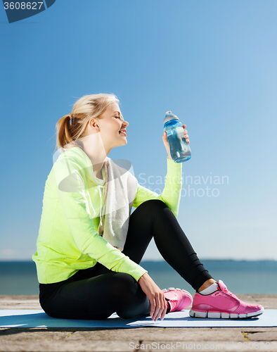 Image of woman drinking water after doing sports outdoors