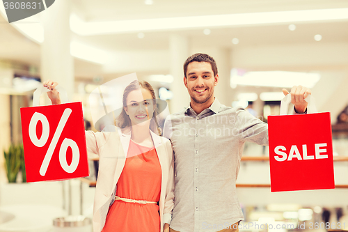 Image of happy young couple with red shopping bags in mall