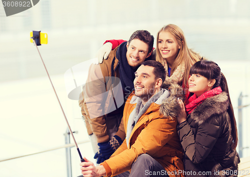 Image of happy friends with smartphone on skating rink