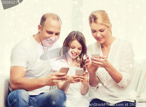 Image of happy family with smartphones at home
